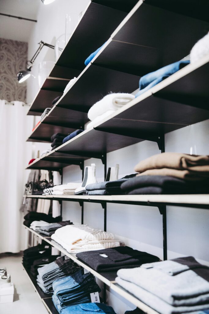 Home Neatly organized shelves with folded clothes in a contemporary store setting.